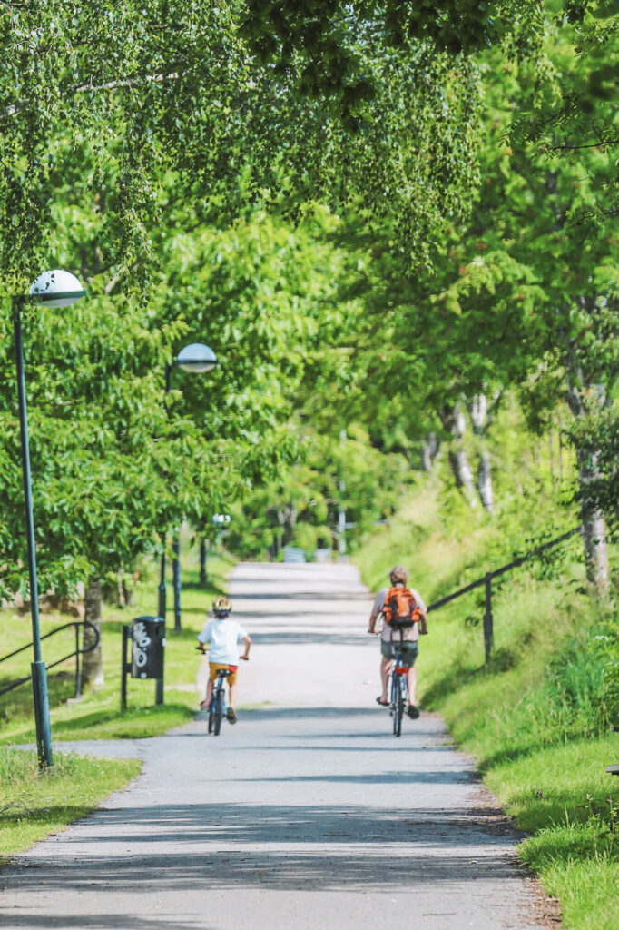 En gångväg i en grönskande miljö med två personer som cyklar bort från kameran