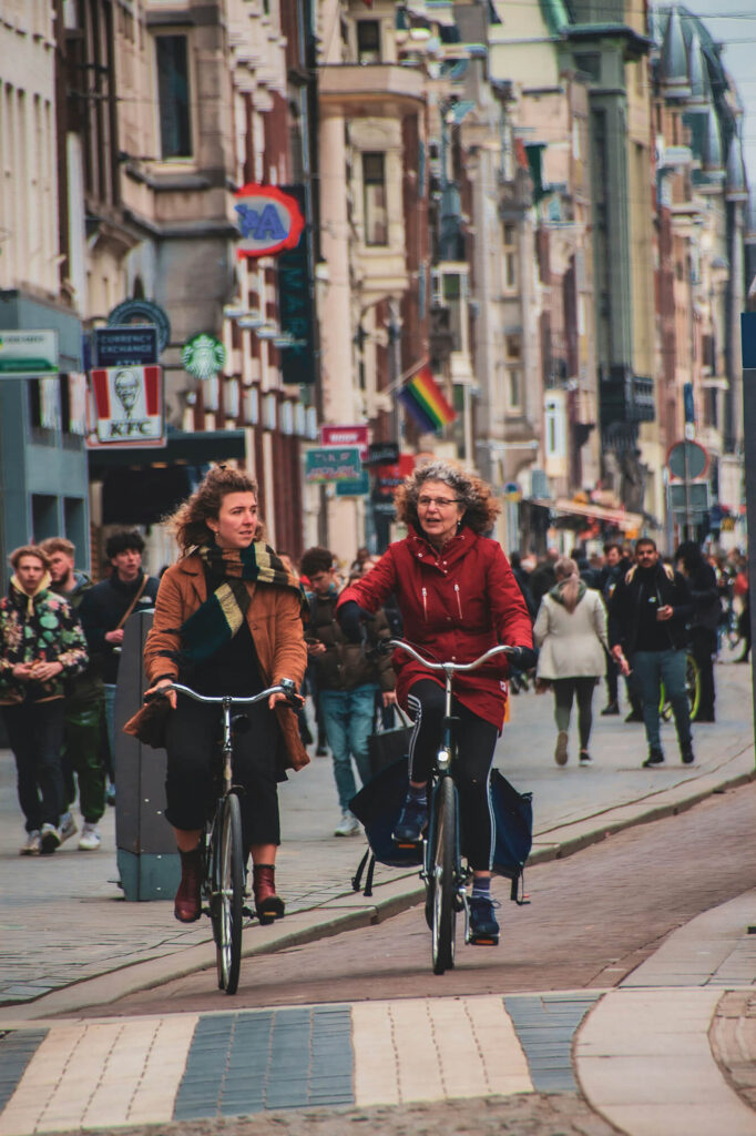 Två personer cyklar genom en stad med mycket folk