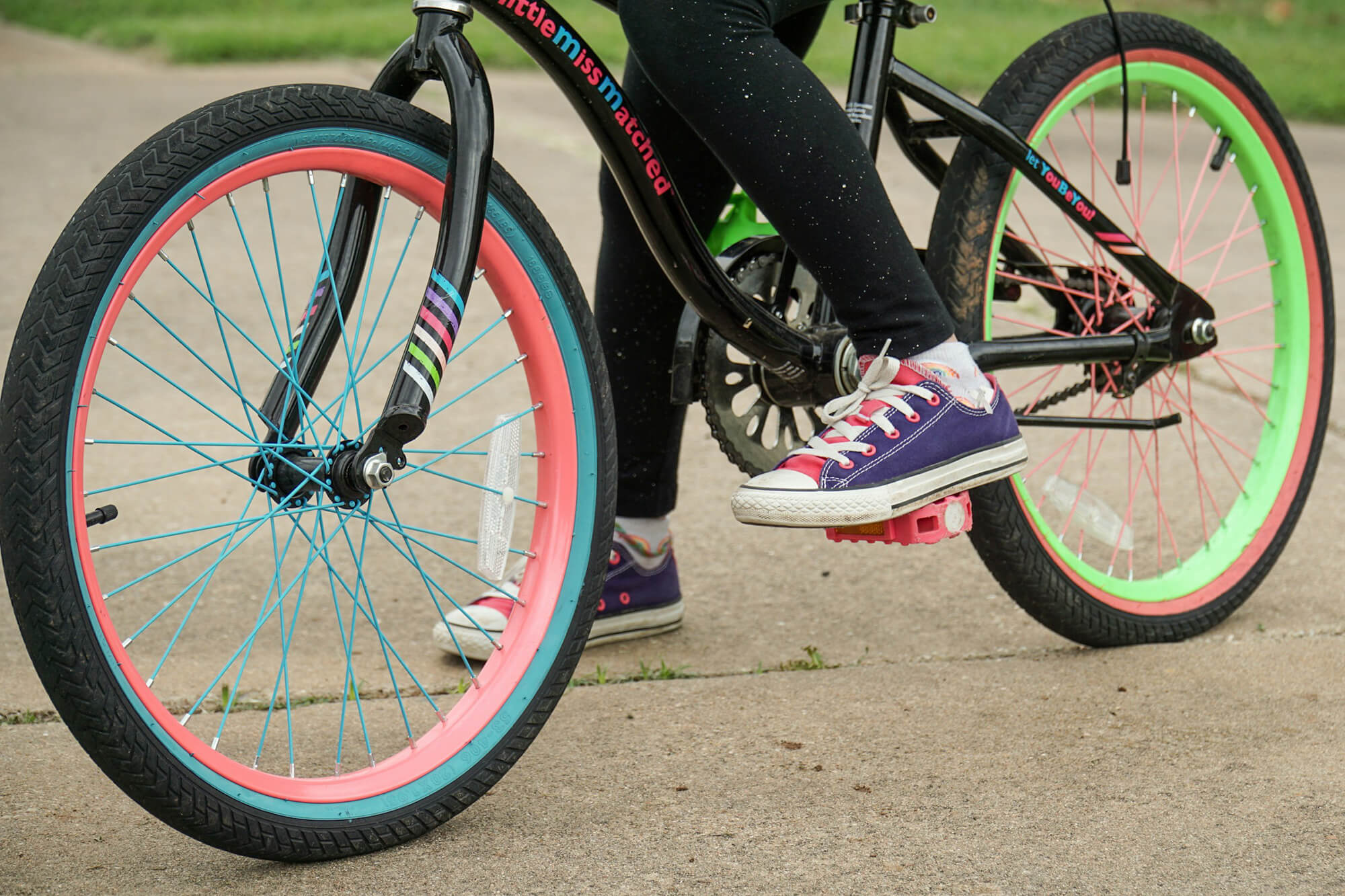 Närbild på en färgglad cykel och fötter som ska börja cykla