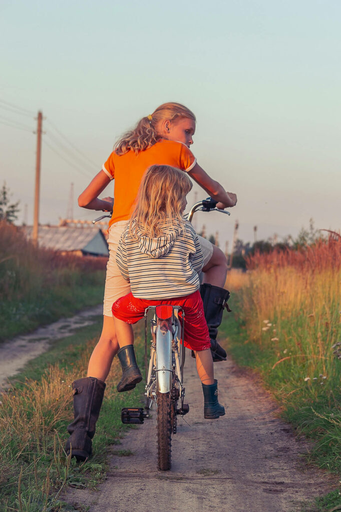 Två barn med en cykel över en äng